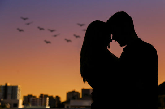 Couple standing hugging each other with a sunset in background