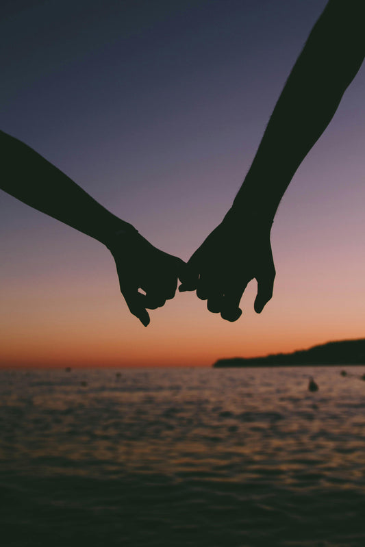 Couple holding hands by the sea with blue and orange sunset