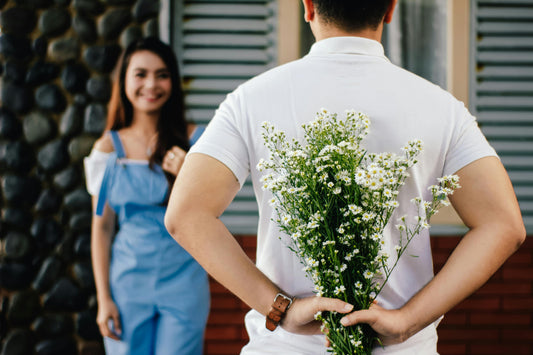 Man holding flowers for girlfriend with brown hair in blue dungarees